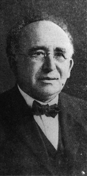 Black and white photo of Rabbi Emanuel (Ephraim) Schreiber, wearing a suit coat, a white shirt, bow tie, and glasses. 